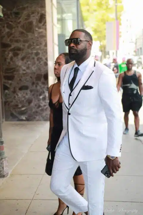 A man walking into a building wearing a custom black and white SMH Atelier suit