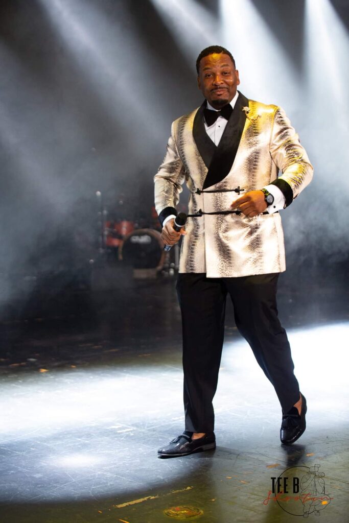 A man standing on stage in a snake print tuxedo