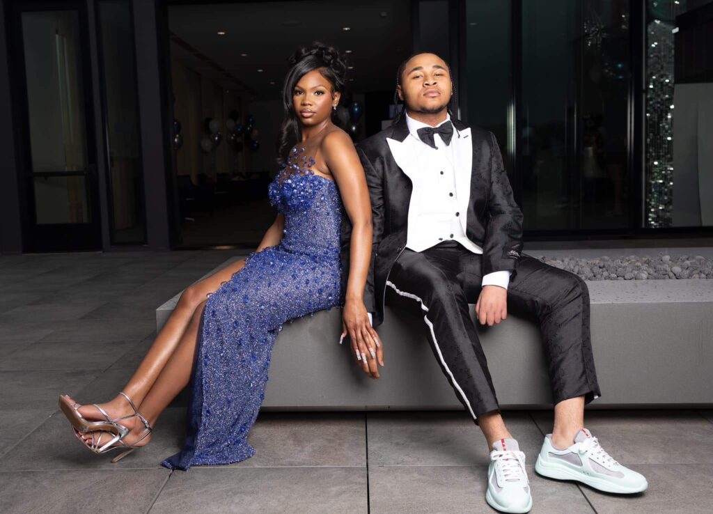 A boy and girl sitting wearing a black and white tuxedo and Blue gown