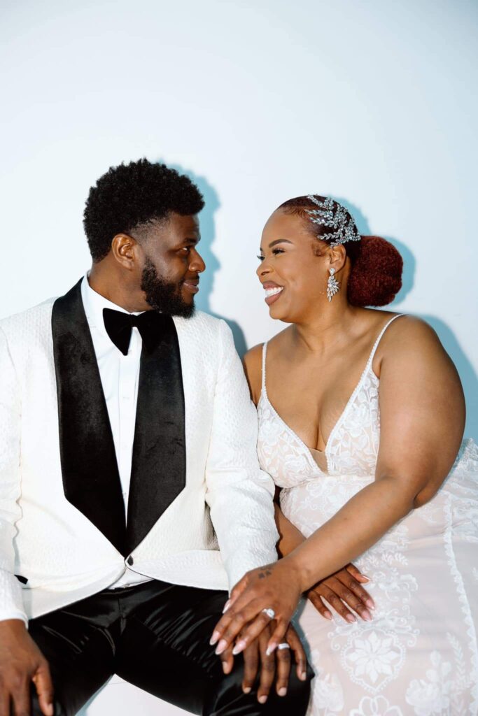 A bride and groom sitting and staring into each others eyes.