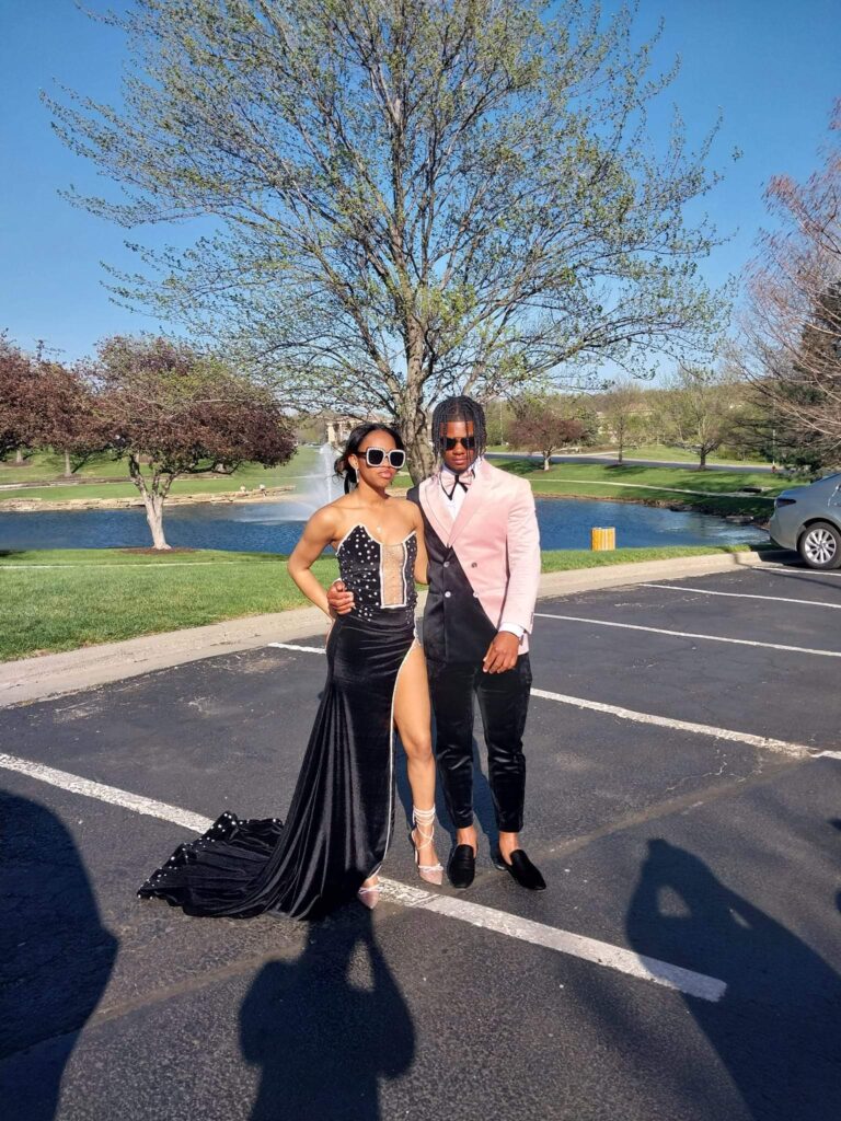 A man wearing a pink and black suit standing with a girl in a black gown