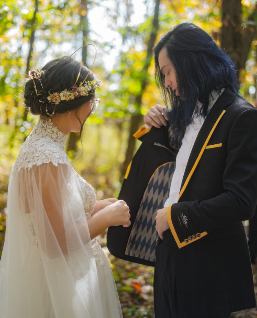 A man showing the inside of his custom suit to a women in a gown,